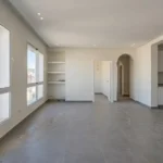 Appartement neuf avec sol poussiéreux et cuisine aménagée nécessitant un nettoyage de fin de chantier avant emménagement.