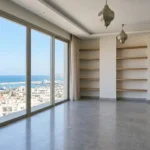 Salon d'un appartement moderne avec vue sur la mer, parfaitement propre et prêt à être emménagé suite à un nettoyage de fin de chantier.
